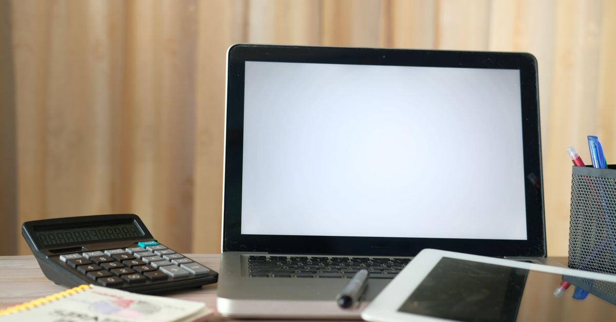 Organized office desk with a laptop, calculator, and tablet ready for business tasks.